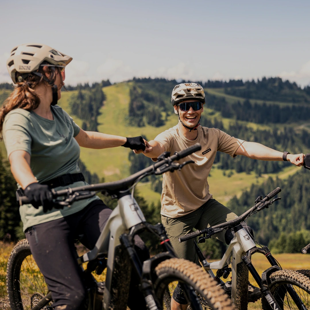 Gruppe von Radfahrerinnen macht eine Pause und genießt die Aussicht auf eine Hügellandschaft.