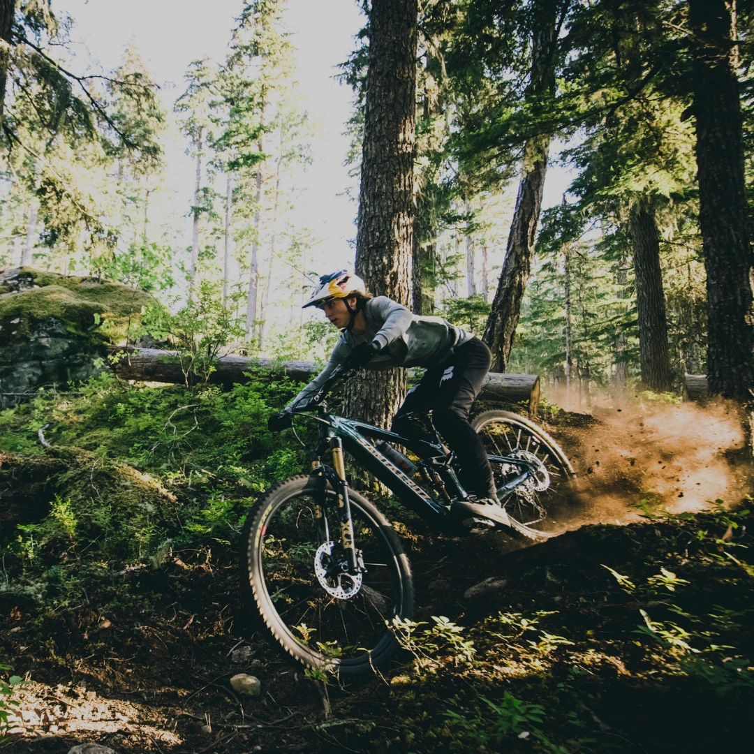 Mountainbiker fährt technisch anspruchsvollen Trail durch einen schattigen Wald.